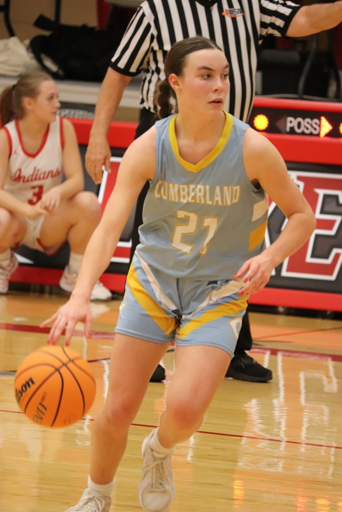 Pictured is JC dribbling the ball with her right hand and going right from the top of the key. There is a ref and a player in the background of the picture.