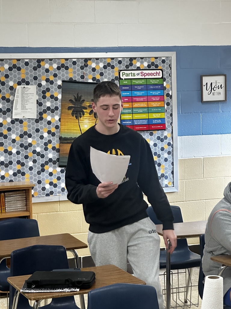 A student is standing and reading from a piece of paper.