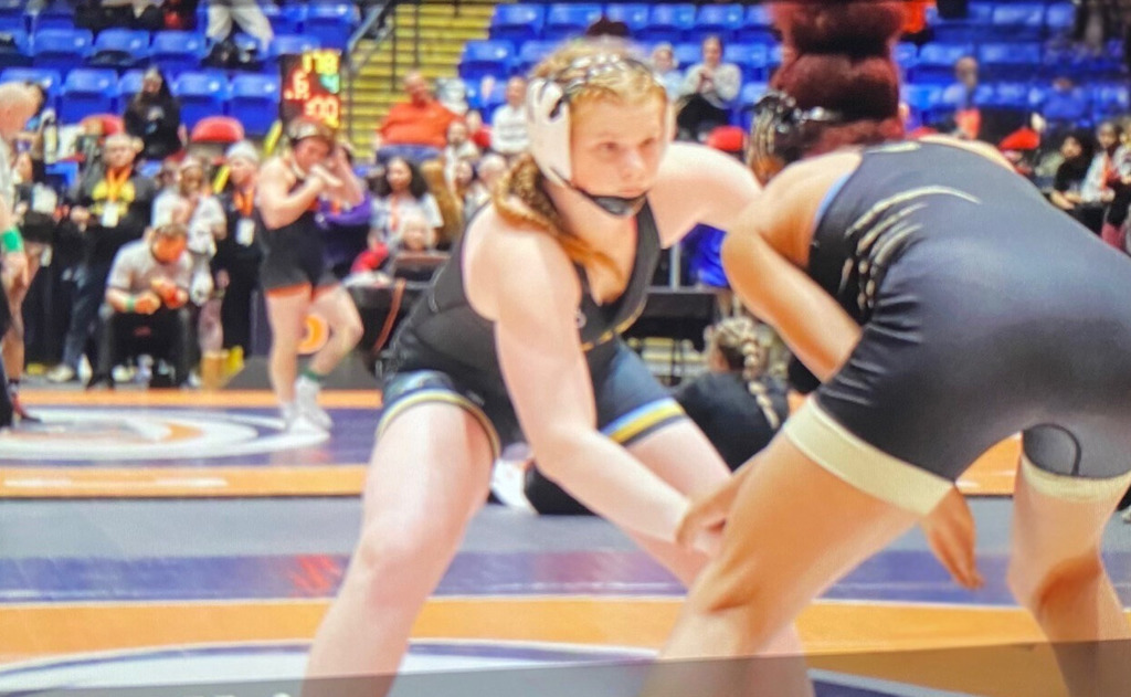 Opponent is holding NB's arm. NB and opponent are bent over looking at each other in the eyes. 