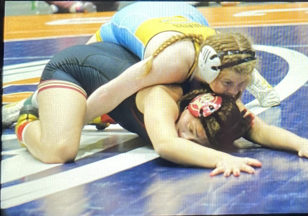 NB is on the back of the opponent. She has her hands around the opponent's waist. 