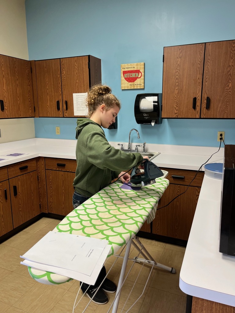 A student is ironing her fabric on an ironing board.