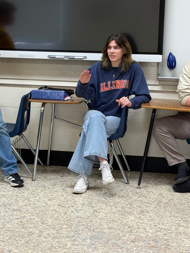 A student is sitting at the strongly agree wall and explaining her opinion. 