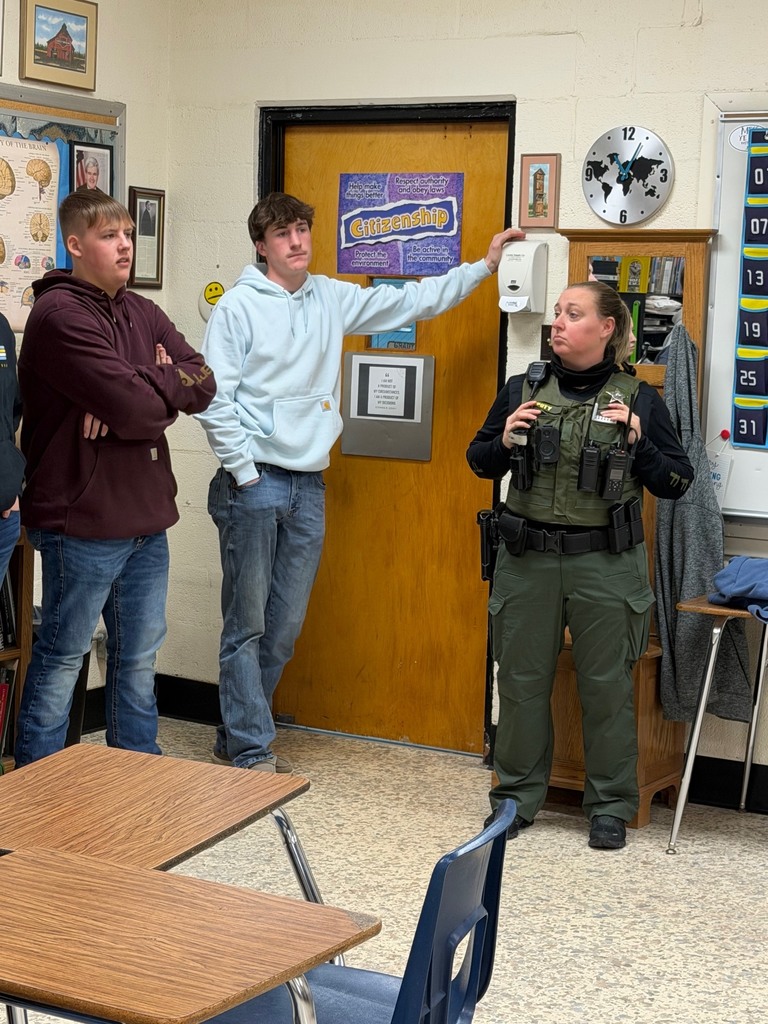 Two students and the SRO are  standing at the agree wall and one is explaining his opinion. 