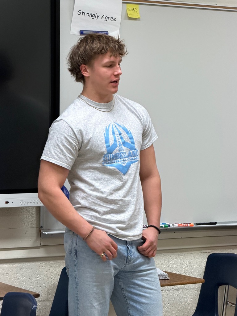 A student is standing at the strongly agree wall and explaining his opinion. 