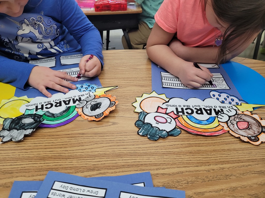 Two students are coloring their March in like a lion out like a lamb poster. 