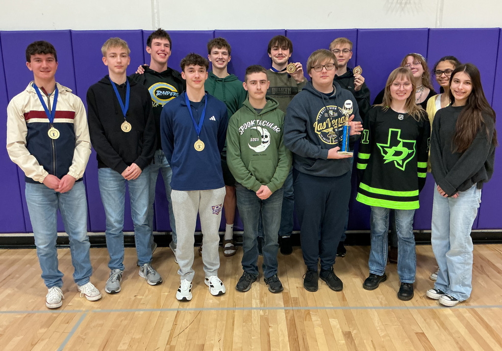 The 13 members of the Aces team are standing together. One is holding the 2nd place trophy. The individual winners are displaying their medals. 