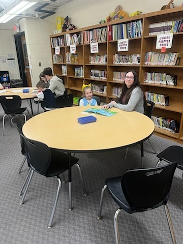 Older students are reading books to younger students. 