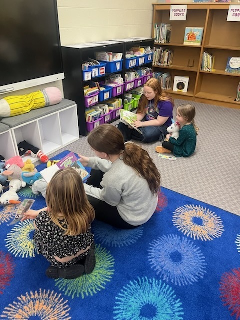 Older students are reading books to younger students. 