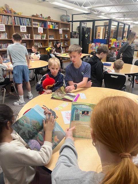 Older students are reading books to younger students. 