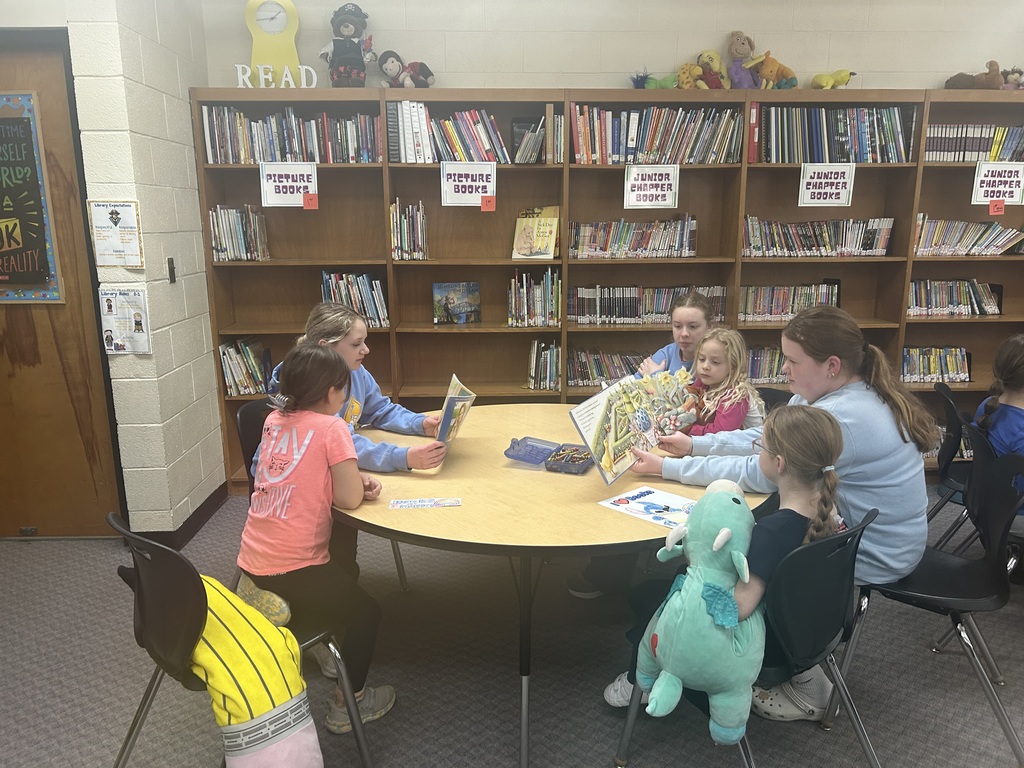Older students are reading books to younger students. 