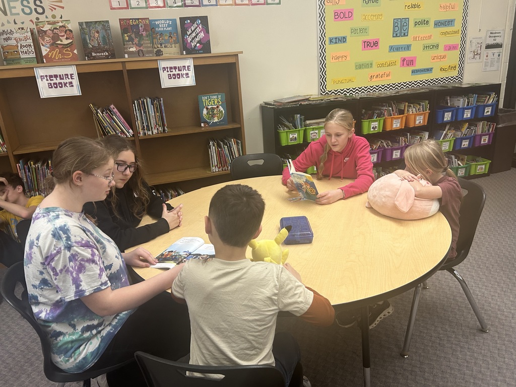 Older students are reading books to younger students. 