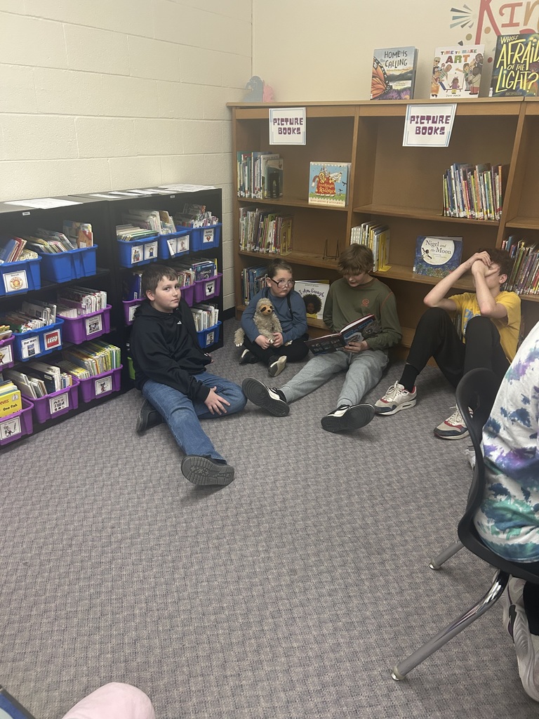 Older students are reading books to younger students. 