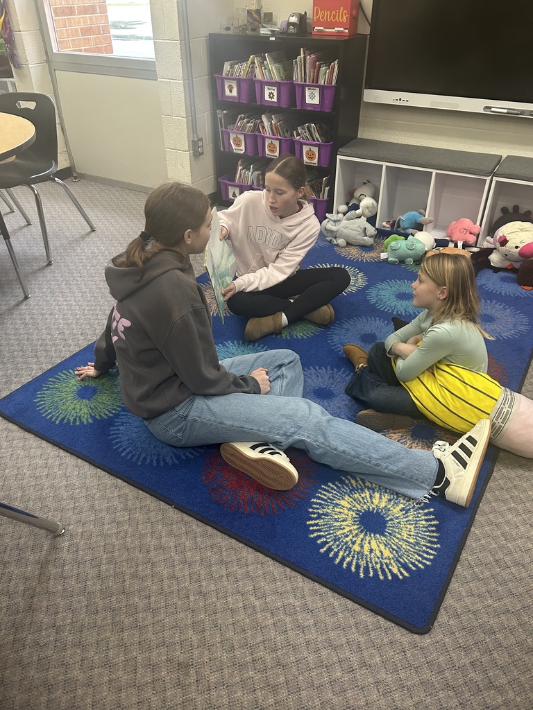 Older students are reading books to younger students. 