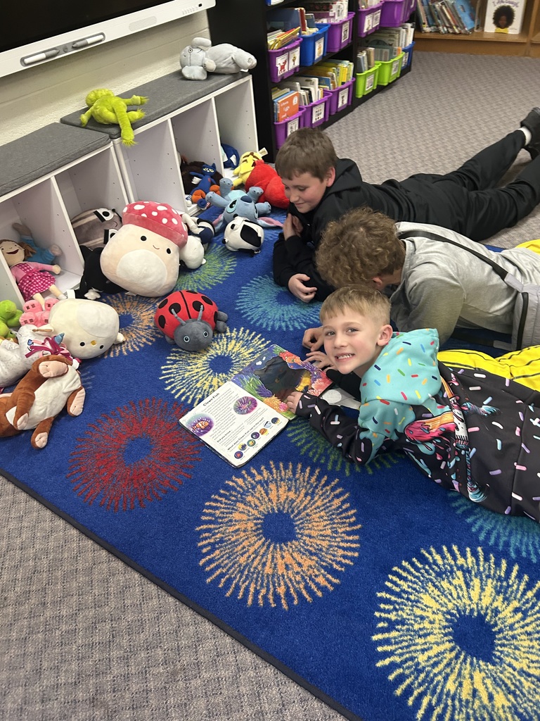 Older students are reading books to younger students. 