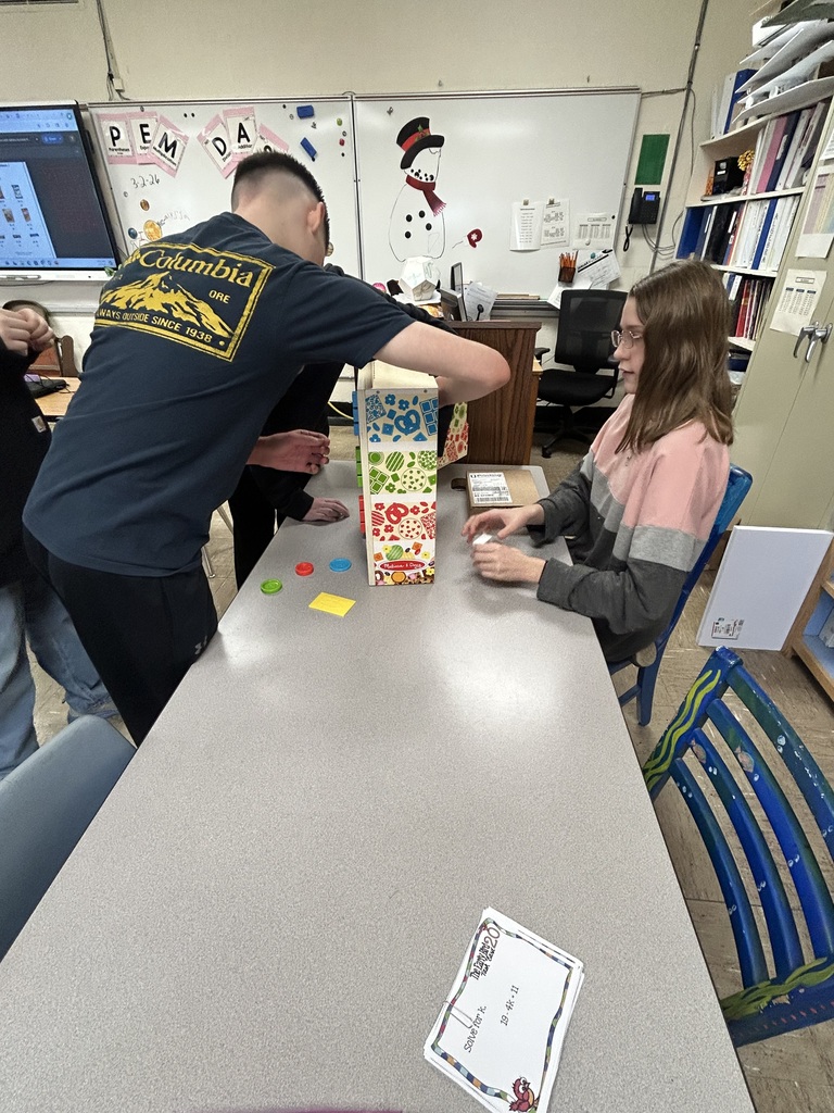 A student is refilling the vending machine. Another student is watching on. 