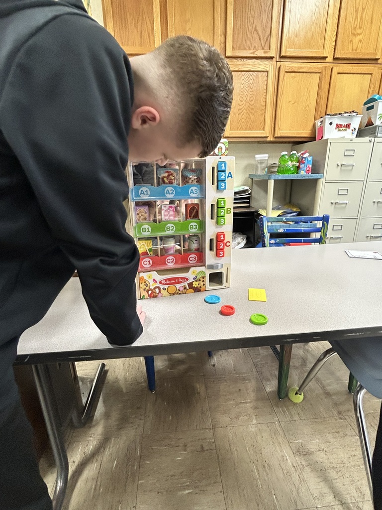 A student is waiting for the item to come out of the vending machine. 