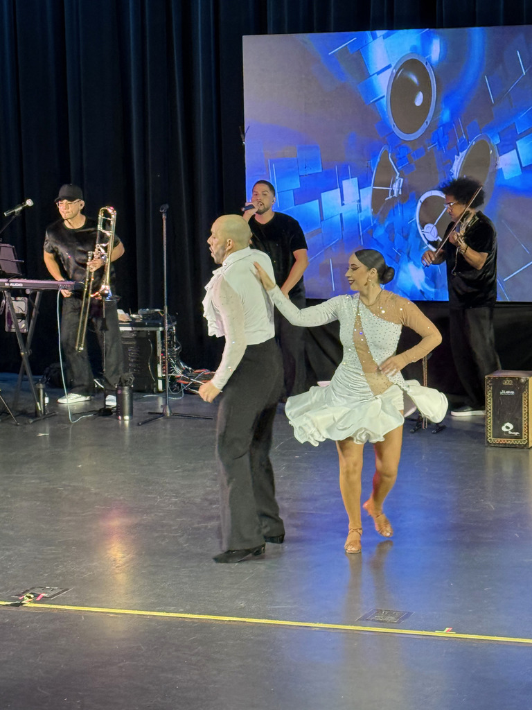 Two are dancing to Spanish music. The band is playing in the background. 