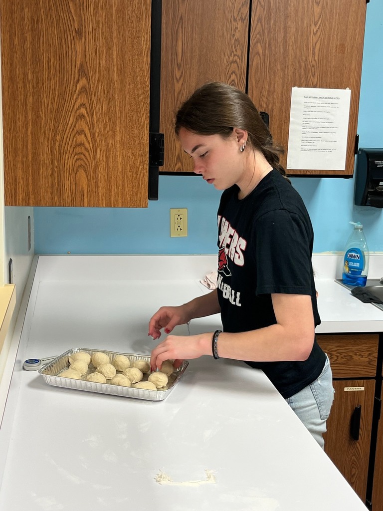 A student is placing rolls on a pan. 