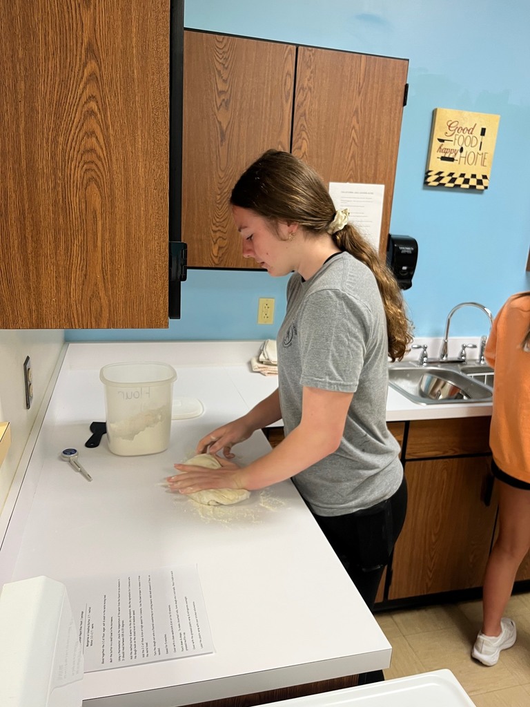 A student is kneeding the dough. 
