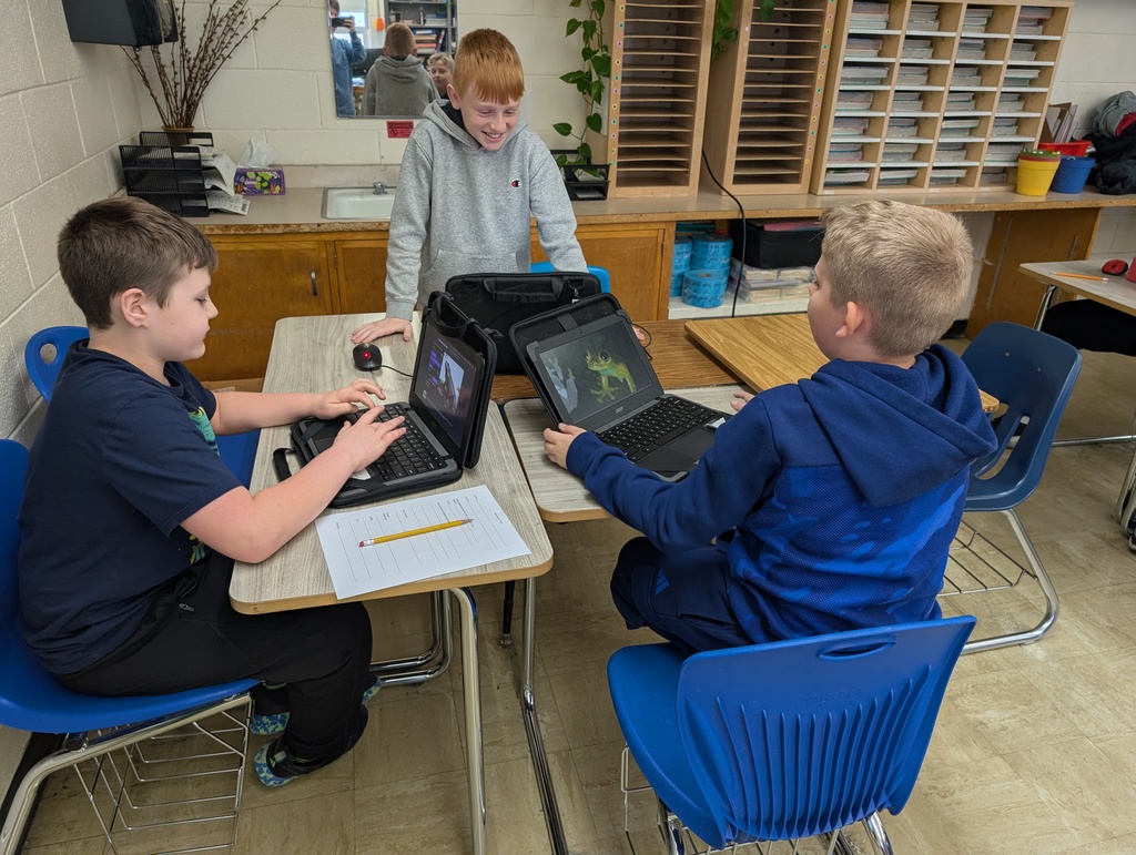 A group of three students are sitting at desks together. Each is working on a shared document on their Chromebook. 