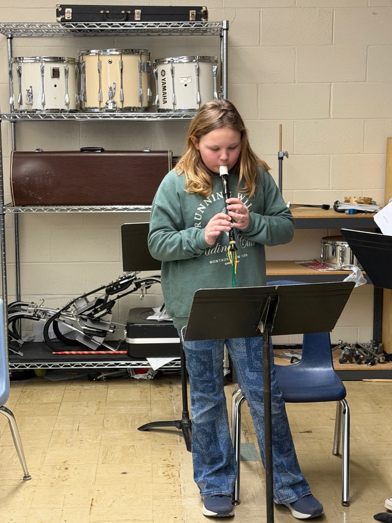 A student is standing in front of a music stand playing the recorder.