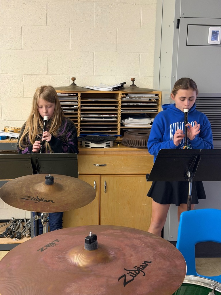 Two students are standing in front of music stands playing the recorder.