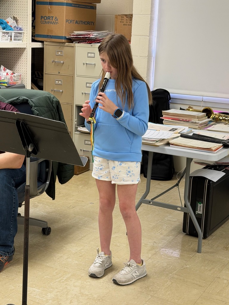 A student is standing in front of a music stand playing the recorder.