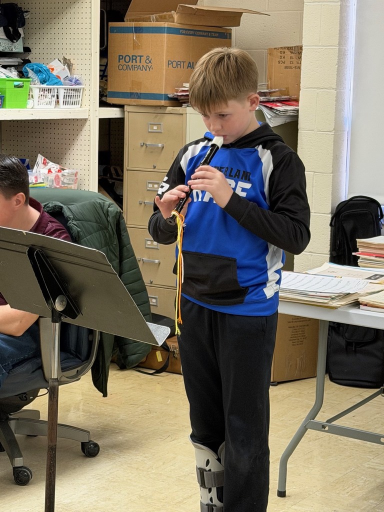 A student is standing in front of a music stand playing the recorder.
