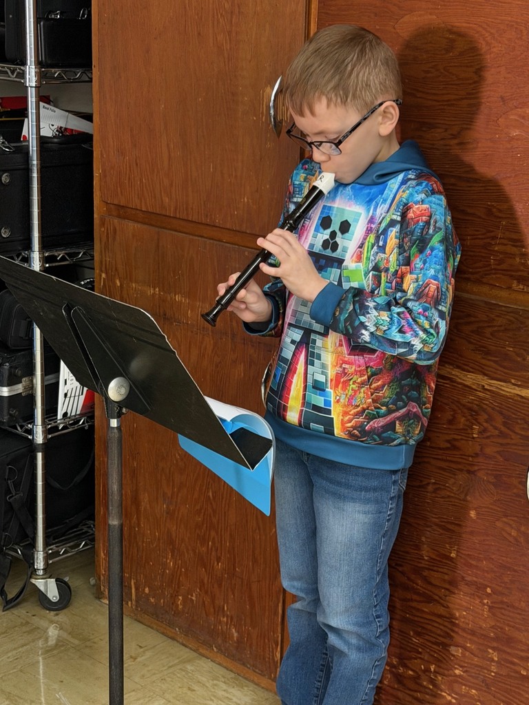 A student is standing in front of a music stand playing the recorder.
