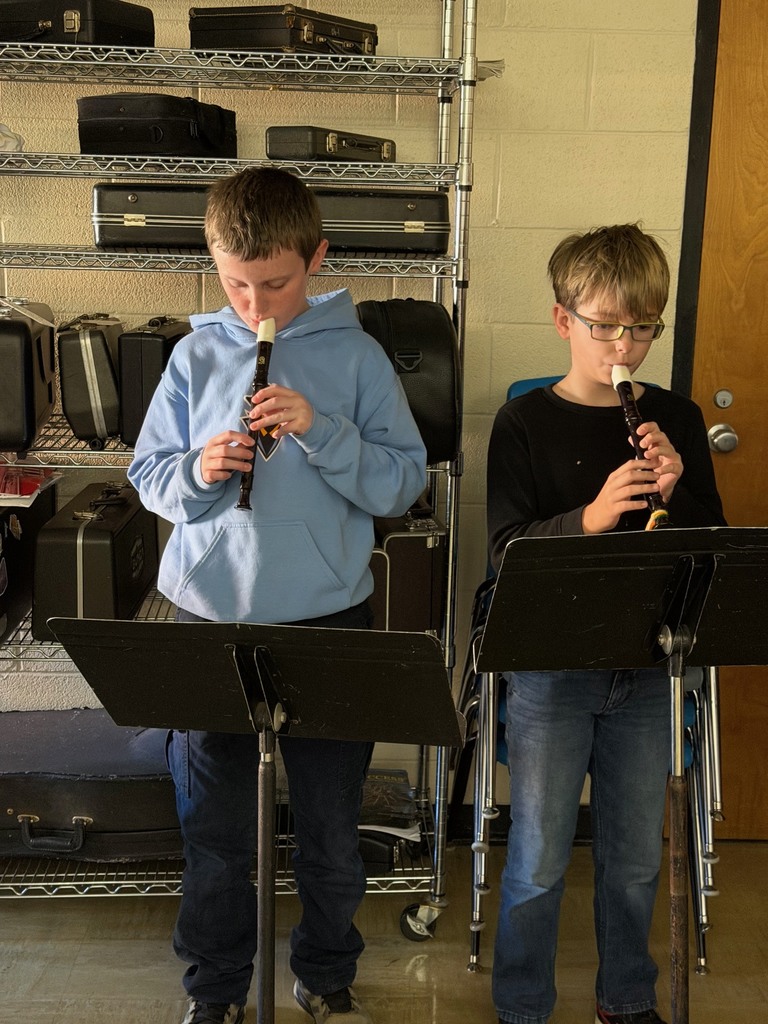 Two students are standing in front of music stands playing the recorder.