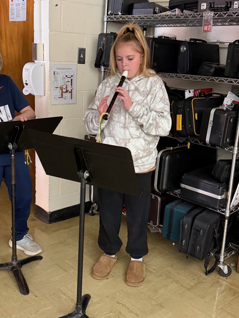 A student is standing in front of a music stand playing the recorder.