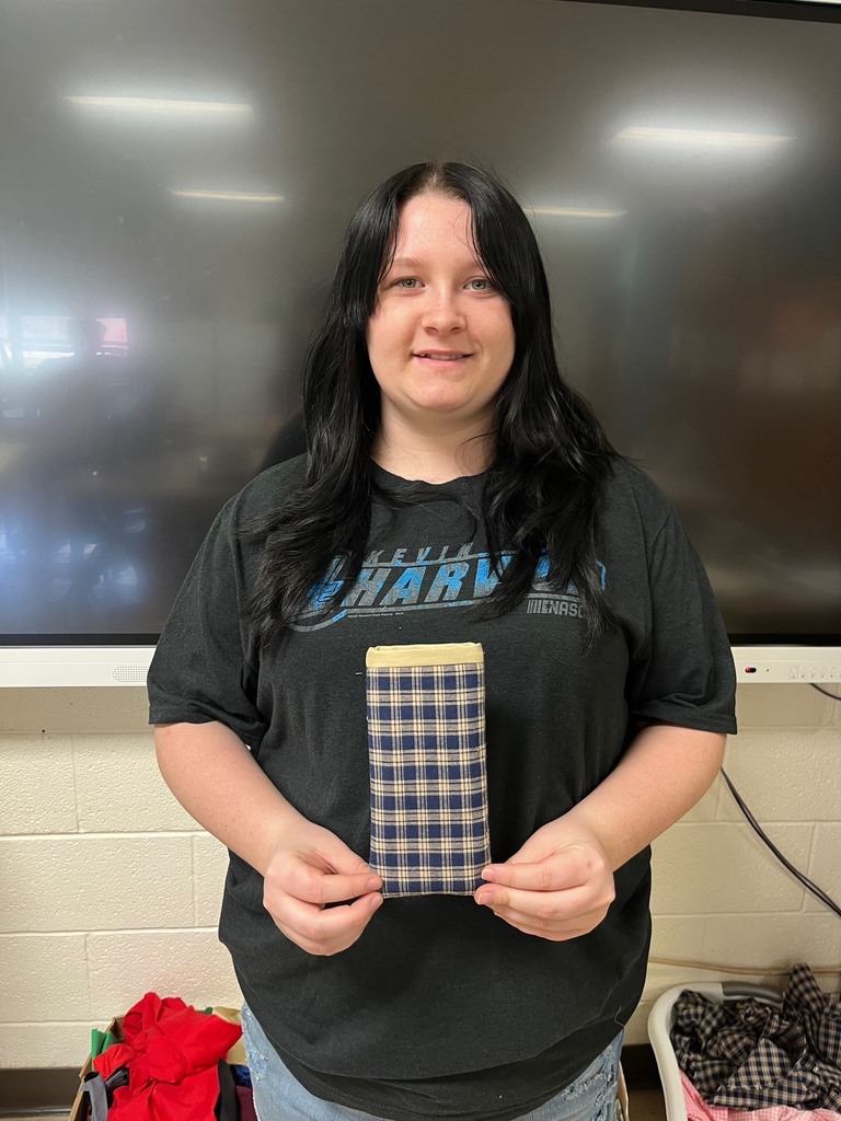 The student is holding an eyeglasses case made of scrap material. 