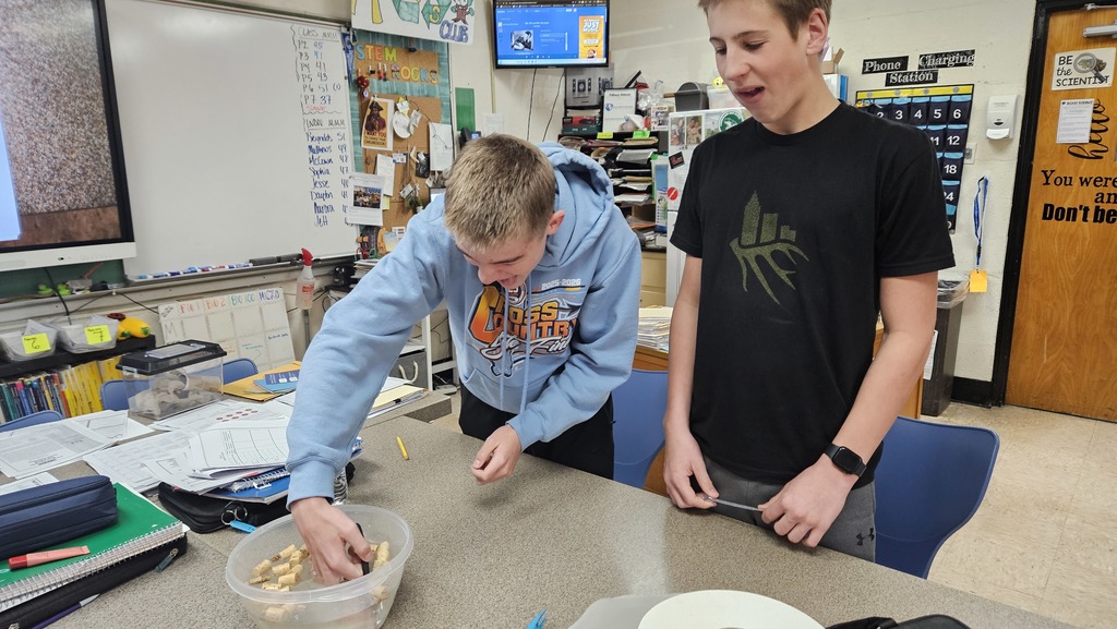 Two students are using their hands to get items out of the water.