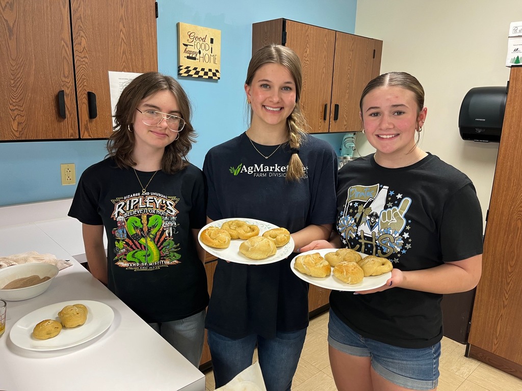 Three students are holding two plates of finished pretzels.