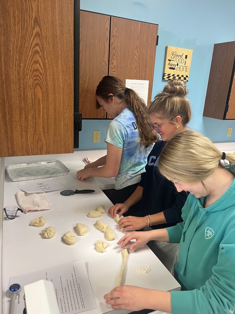 Three students are shaping pretzels.