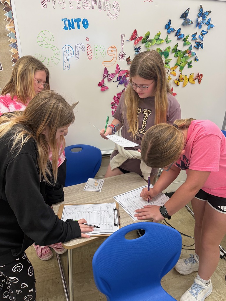 Four students are gathered around a desk solving a task card.