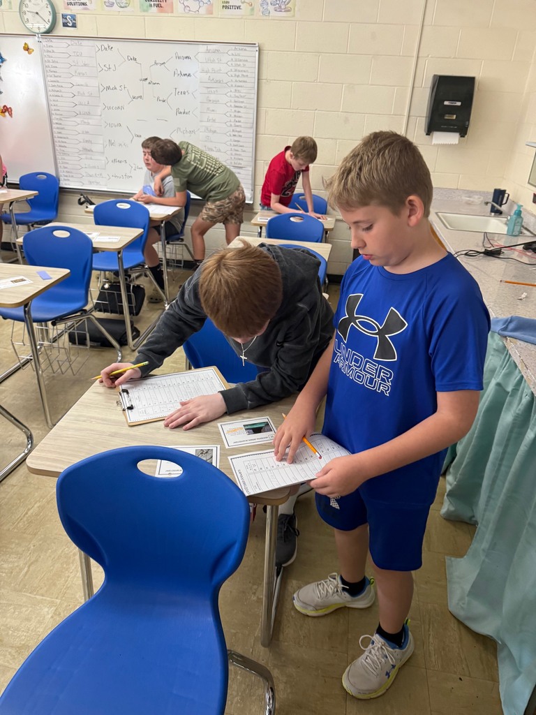 Two students are gathered around a desk solving a task card.