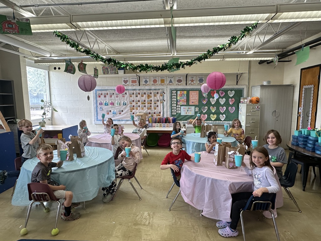 The students are sitting at their tables holding up their punch cups.