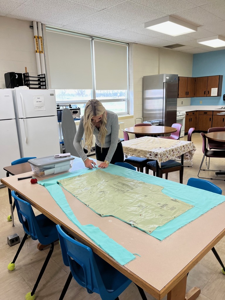 A student is cutting out the fabric using a pattern.