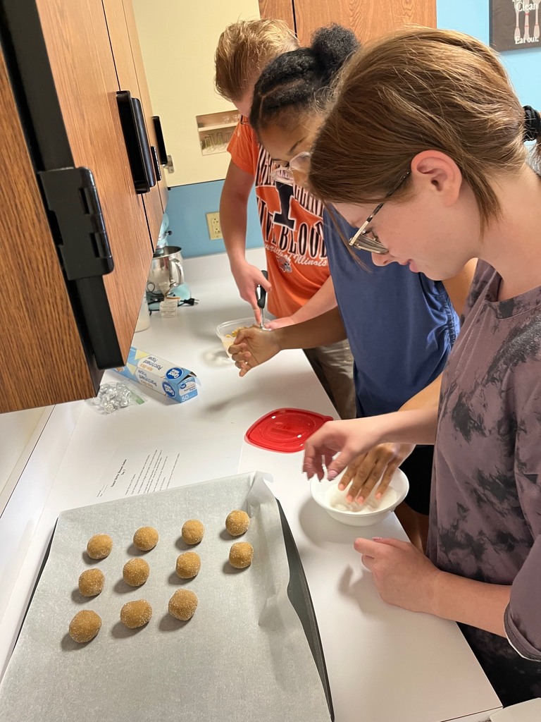 Students are putting dough in sugar and placing them on the baking sheet.