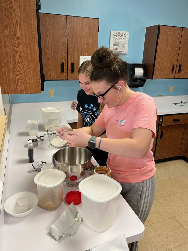Two students are rolling dough into balls.