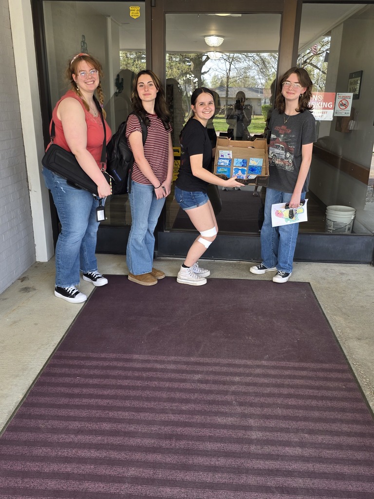 Art club members are standing in front of the nursing home with finished tiles.