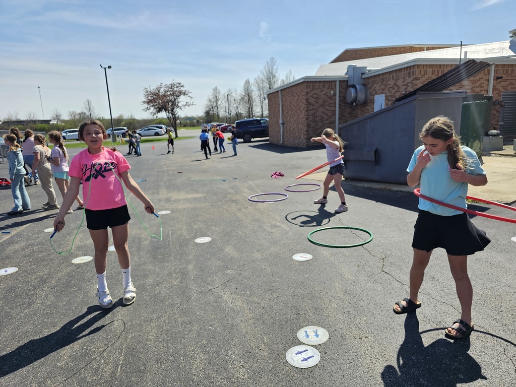 A group of students are jumping rope and hula hooping. 