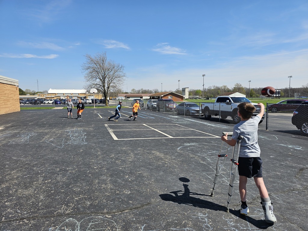 A group of students are playing football on the blacktop. 