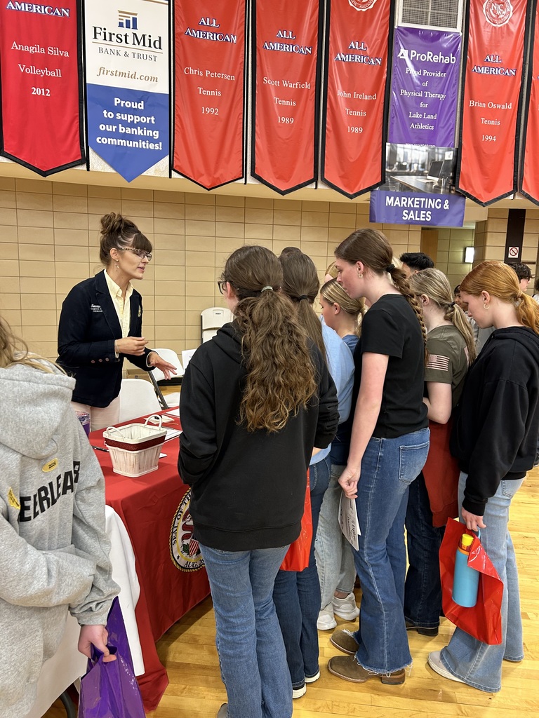 A group of students are speaking with one of the presenters at her table.
