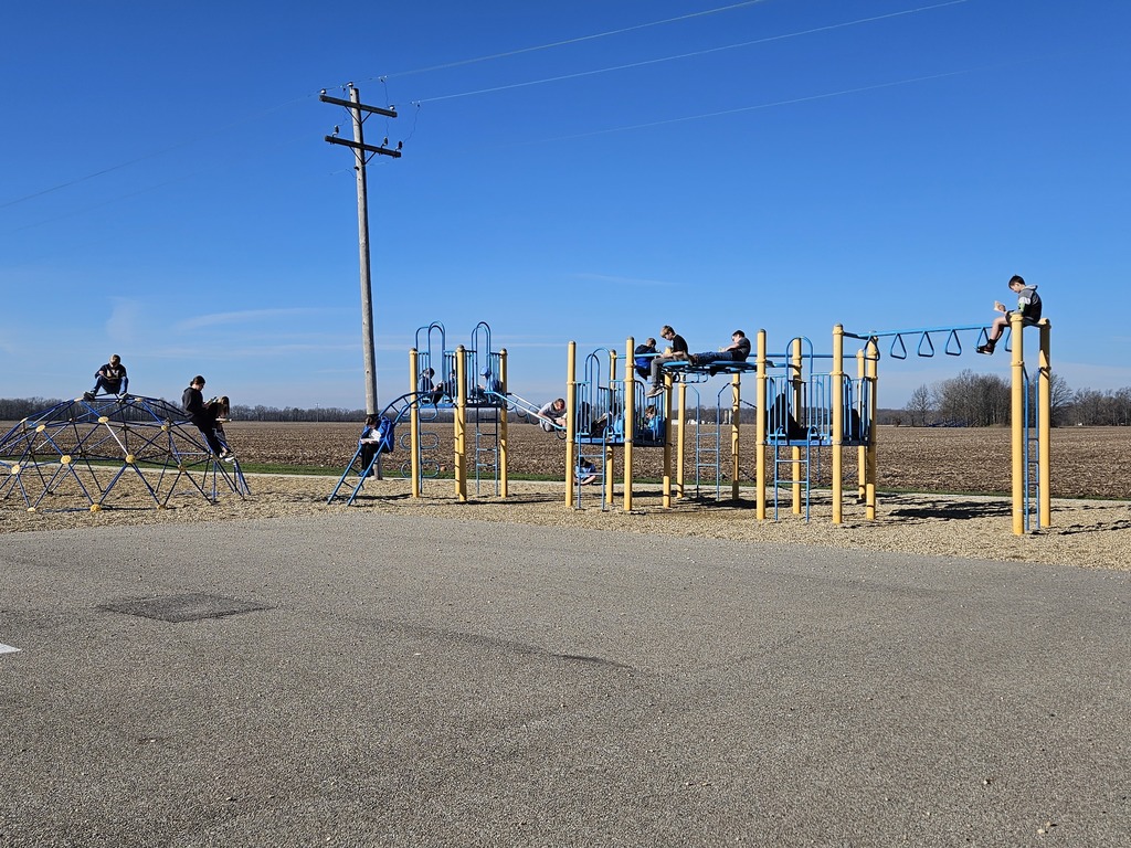 Students are on the plalyground equiptment reading their books.