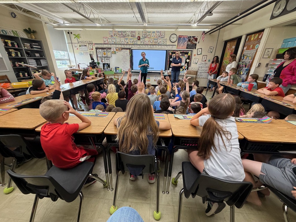The two conservationists are speaking to a room full of third graders. 