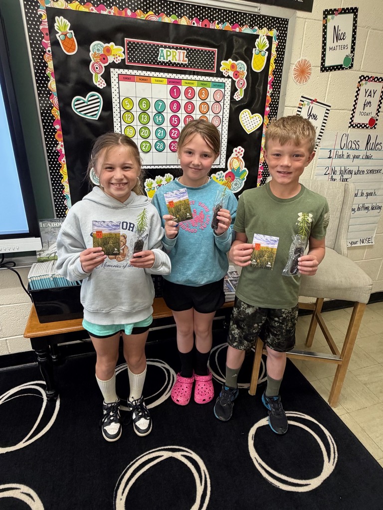 Three students are each holding a tree and seed packet.