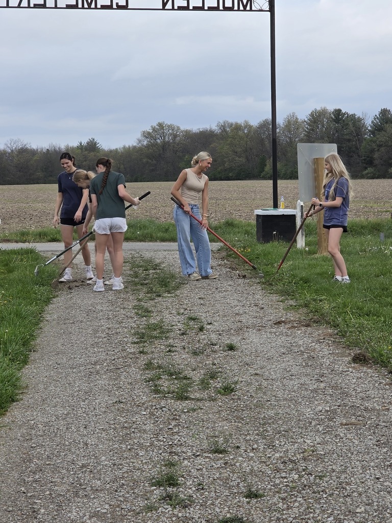 Five students are raking at the cemetery.