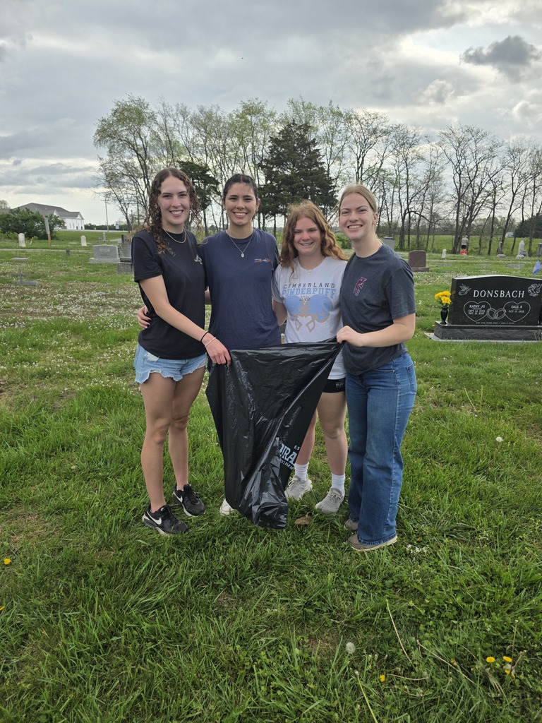 Four students are picking up trash at the cemetery.
